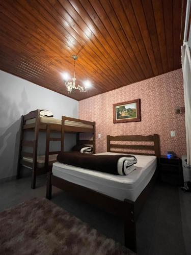 a bedroom with two beds and a wooden ceiling at Refugio Familiar em Monte Verde in Monte Verde