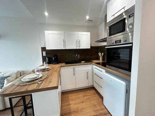 a kitchen with white cabinets and a wooden counter top at La Suite Vienne, chic et calme in Panazol