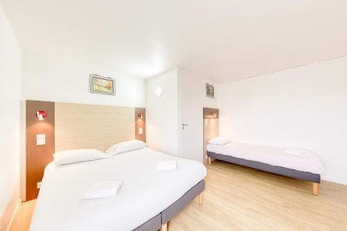 two beds in a room with white walls and wooden floors at FASTHOTEL ROISSY CDG SUD - Claye Souilly in Claye-Souilly