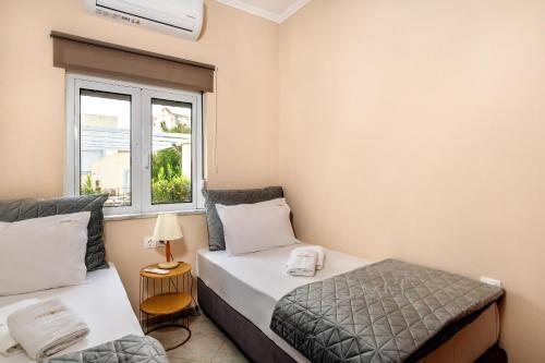 Un dormitorio con dos camas y una ventana. en Grekodes Kera, seafront villa, en Kalyves