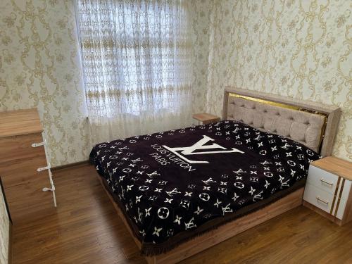 a bedroom with a bed with a black and white comforter at Karimbek Guest house by SamApart in Samarkand