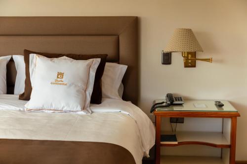 a bed with a white pillow and a table with a phone at Gran Hotel Continental in Cajamarca