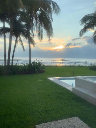 a resort with a pool and palm trees and the ocean at Beachfront house Private beach Pool 6 people in El Zapote