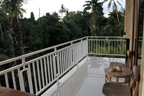 a balcony with a white railing and a table and chairs at Hanaka Riverside Ubud in Ubud