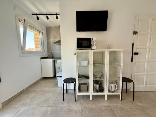 a white cabinet with two stools and a tv on a wall at GOLDEN COAST CALAFELL 2 in El Vendrell
