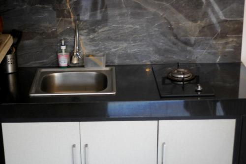a kitchen counter with a sink and a stove at Hanaka Riverside Ubud in Ubud