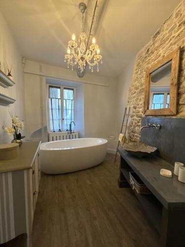 une grande salle de bains avec une grande baignoire et un lustre dans l'établissement Le Mas de Cabrières, à Cabrières-dʼAvignon
