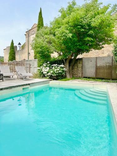 une piscine bleue avec deux chaises et un arbre dans l'établissement Le Mas de Cabrières, à Cabrières-dʼAvignon