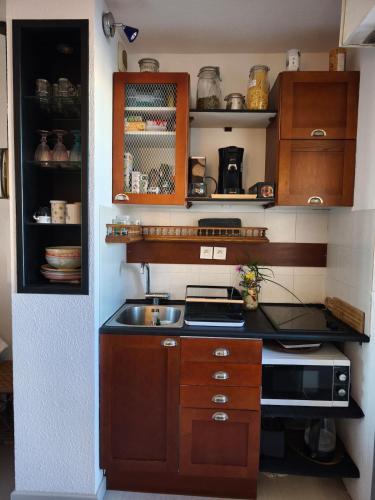 Elle comprend une petite cuisine avec des placards en bois et un évier. dans l'établissement Appart neuf et cosy 2 personnes center port Cap d'Agde, au Cap d'Agde