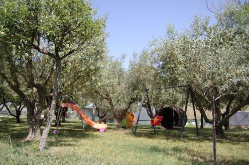 a playground in a park with trees and a slide at Il Giardino Degli Ulivi in Appignano