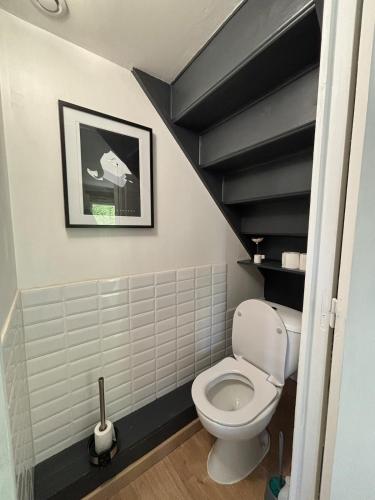 a bathroom with a white toilet and black stairs at Stone House in Plélan-le-Petit