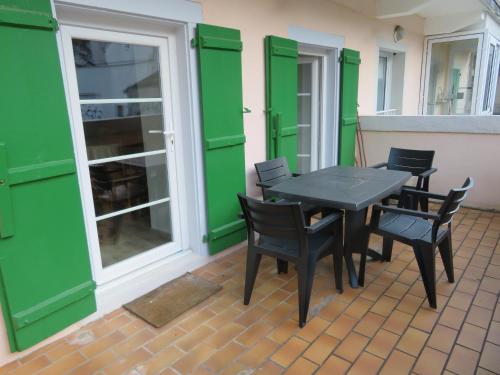 une table et des chaises sur une terrasse avec volets verts dans l'établissement Appart 6 personnes, 2ch, parking, centre-ville, à Cauterets