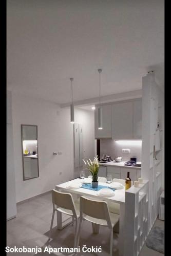 a white kitchen with a white table and chairs at Apartmani Čokić Sokobanja in Soko Banja