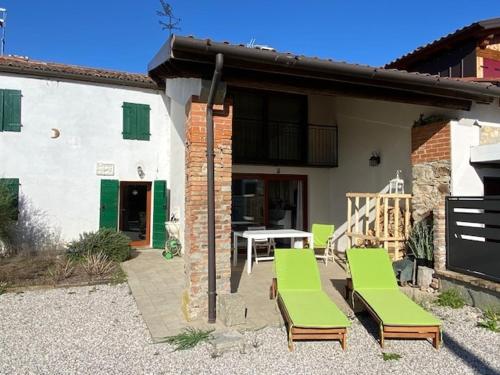a patio with green chairs and a table and a building at Casa delle Fate - between Nature and Harmony in Boccon