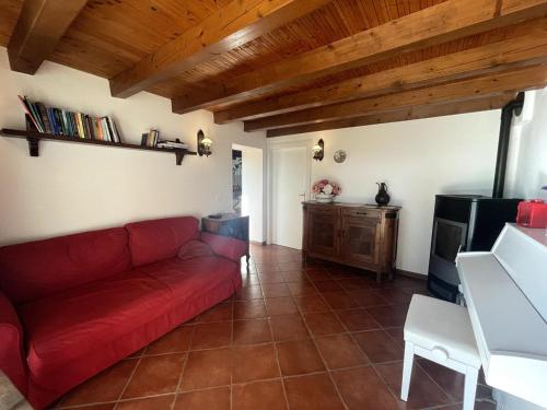 a living room with a red couch and a table at Casa delle Fate - between Nature and Harmony in Boccon