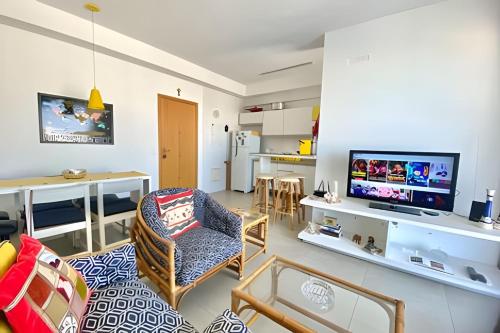 a living room with a couch and a tv in it at Brisa à Beira-Mar: Desfrute do melhor no Gonzaga in Santos