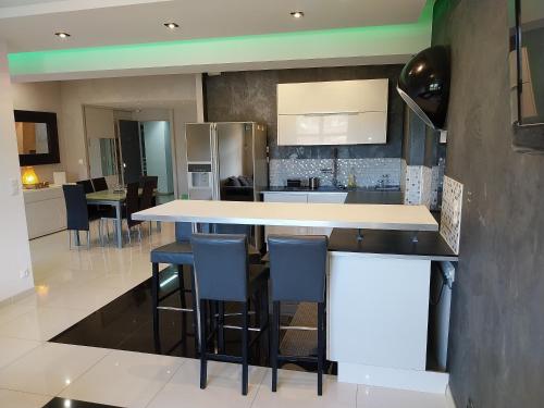 une cuisine avec un comptoir et quelques tabourets bleus dans l'établissement Spacieux appartement moderne, à La Garde