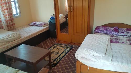 a small room with two beds and a table at Friendship Home Stay in Kathmandu