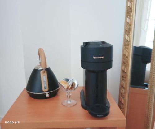 une cafetière noire sur une étagère avec un verre à vin dans l'établissement Ostal Arriatge, à Lézat-sur-Lèze