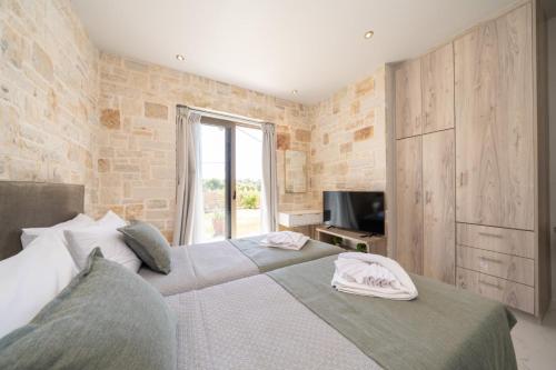 a bedroom with two beds and a television in it at Blue Private Stone Villa Skala in Skala Kefalonias