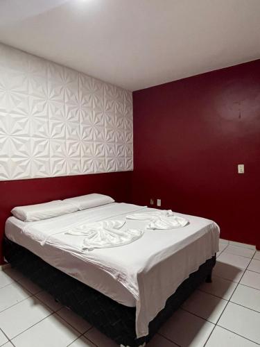 a bedroom with a large bed with a red wall at Hotel Pousada Baturité FORTALEZA in Fortaleza