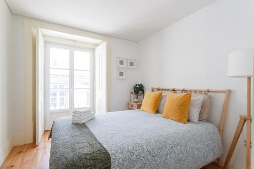 a bedroom with a bed with yellow pillows and a window at Central Bedroom in Shared House in Chiado - Historic Center of Lisbon in Lisbon