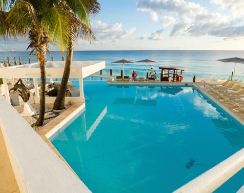 a swimming pool with the ocean in the background at Paradisiaca Suite Cancun - BEACH CONDO - 4PX in Cancún