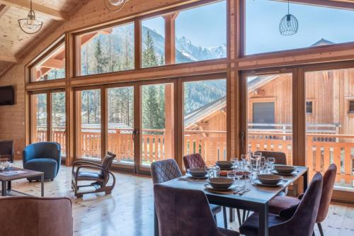 - une salle à manger avec une table, des chaises et de grandes fenêtres dans l'établissement Large chalet for 10 with beautiful garden, à Chamonix-Mont-Blanc