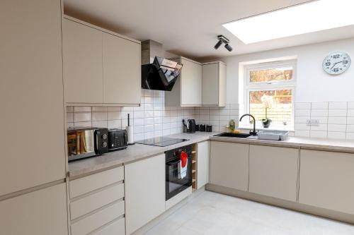 a kitchen with white cabinets and a sink and a microwave at Peakstone House in Sheffield