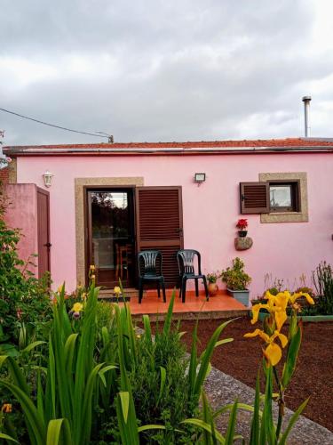 a pink house with two chairs on a patio at Pêssego - AL in Arouca