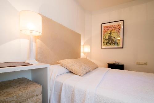 a small bedroom with a white bed and a lamp at Hostal Casa Alborada in Conil de la Frontera