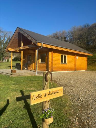 une cabane en bois avec un panneau en face de celle-ci dans l'établissement Le Chalet de Lintignat, à Peyrat-le-Château
