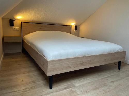 a bedroom with a large bed with white sheets at Slapen in een eeuwen oude Pastorie in Leermens