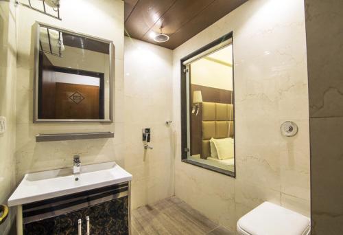 a bathroom with a sink and a mirror and a toilet at Hotel Abhinandan in Mathura