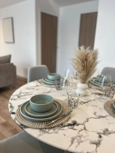 a dining room table with plates and bowls on it at Les gîtes de l'ancienne ferme in Penly