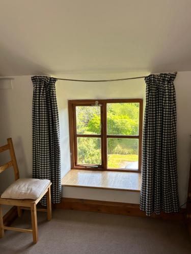 a window with curtains and a chair in a room at Llanerch in Bala