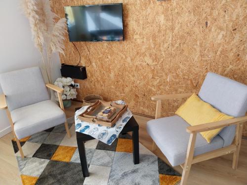 - un salon avec 2 chaises, une table et une télévision dans l'établissement Les Fougères, à Étel