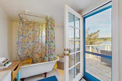 a bathroom with a tub next to a sliding glass door at Rosewater Cottage in Eagledale