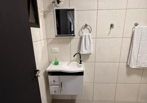 a white bathroom with a sink and a mirror at Quitinete Inteligente No Centro Unidade 03 in Presidente Prudente