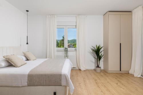 a white bedroom with a bed and a window at Villa Artemis in Plitvička Jezera