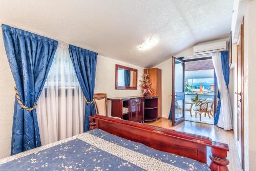 a bedroom with a bed with blue curtains and a balcony at Villa Roses Apartments & Wellness in Ičići