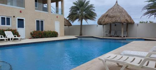 Ein Swimmingpool vor einem Haus mit Stühlen in der Unterkunft Sunset Bliss Suite at Commandeurs in Oranjestad