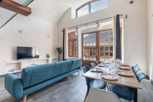 ein Esszimmer mit einem Tisch und einem blauen Sofa in der Unterkunft Le Château Fort 16 in Albertville