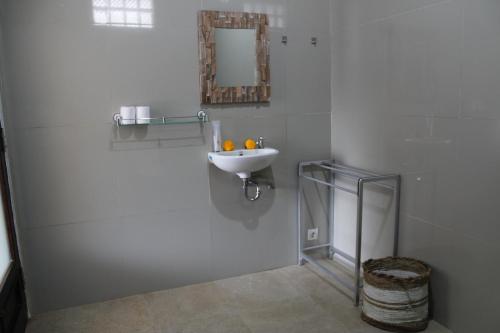 a white bathroom with a sink and a mirror at Hanaka Riverside Ubud in Ubud