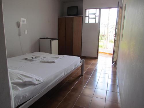 a bedroom with a white bed and a tiled floor at Hotel Imperador in Caldas Novas