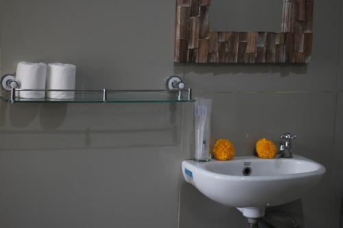 a bathroom with a sink and a shelf with towels at Hanaka Riverside Ubud in Ubud