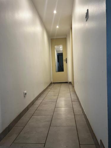 un couloir vide avec une porte et du carrelage dans l'établissement La Maison Téranga au Bourg de Villenave, à Courrejean