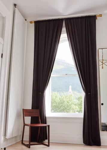 a window with black curtains and a chair in a room at The Wyman Hotel in Silverton