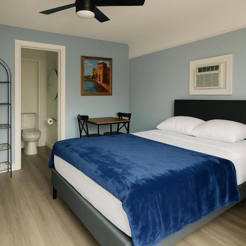 a bedroom with a large bed with a blue blanket at Pousada Suites at Hollywood Beach in Hollywood