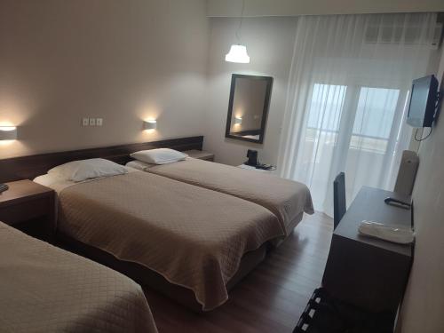 a hotel room with two beds and a flat screen tv at Plaza Hotel in Alexandroupoli